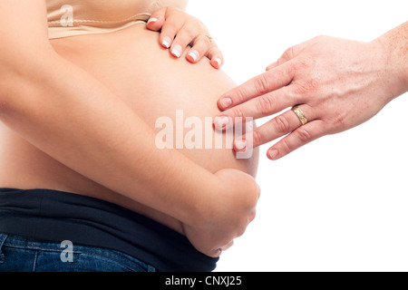 Donna incinta e mano maschio toccando il suo ventre, isolato su sfondo bianco. Foto Stock