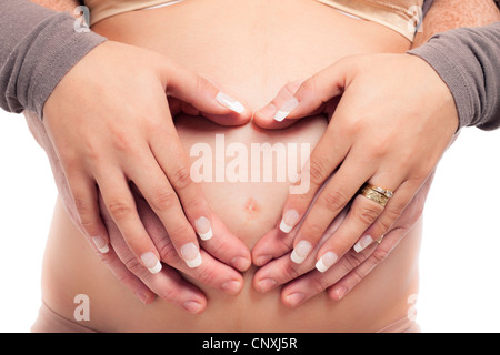 Close up di bella donna incinta e mani toccano il suo ventre. Foto Stock