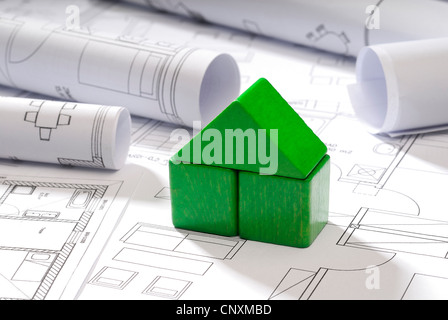 Piccola casa in legno blocchi e blueprint come simbolo di costruzione ecologica. Foto Stock