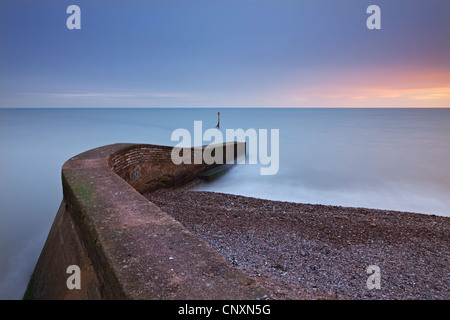 Stone jetty di Sidmouth sulla spiaggia al tramonto, Sidmouth, Devon, Inghilterra. Inverno (gennaio 2012). Foto Stock