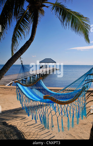 Vista dalla spiaggia di sabbia in un hamock ad una passerella in legno che conduce al mare, Belize, Ambergris Caye Foto Stock