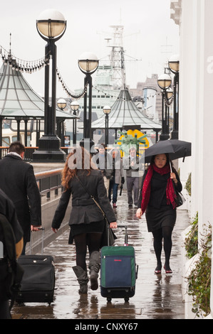 London Bridge , Southbank , Cotton's Center , il Queens a piedi , i pedoni con ombrellone e custodie a piedi nella pioggia da embankment Foto Stock