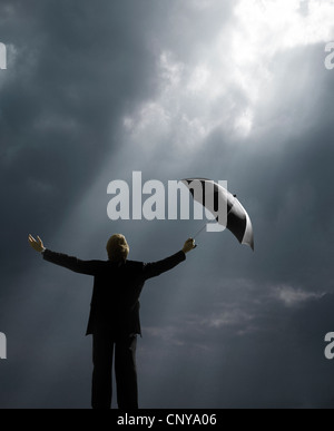 Uomo con ombrello in piedi di raggi di luce solare Foto Stock