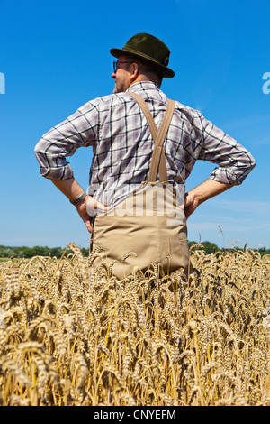 Pane di frumento, coltivati frumento (Triticum aestivum), contenuto agricoltore in piedi nel suo grano maturo con i bracci akimbo, Germania Foto Stock