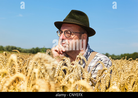 Agricoltore premurosamente seduta in una coppia campo di grano, Germania Foto Stock