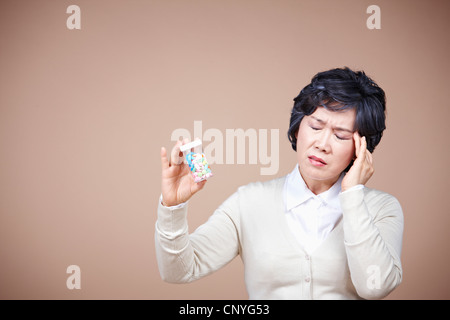 Una vecchia donna che soffre di mal di testa con la medicina Foto Stock