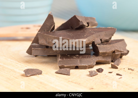 Pezzi di rotture di cioccolato fondente impilati su un tagliere Foto Stock