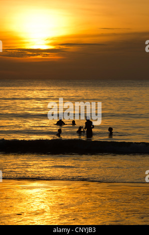 Persone in mare al tramonto, Kamala Beach, Phuket, Tailandia Foto Stock