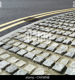 Pietra di superficie in ciottoli accanto a un asfalto stradale rivestita. Foto Stock