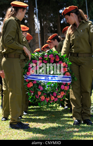 Israeliano soldati femmina portano ghirlande durante una cerimonia commemorativa per soldati caduti durante Yom Hazikaron giorno memoriale per i soldati caduti in Kiryat Shaul ebraica terreno di sepoltura nel nord di Tel Aviv Israele Foto Stock