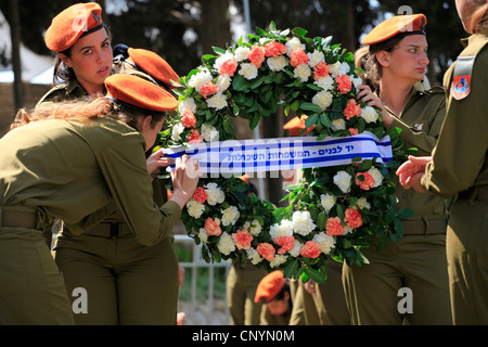 Un israeliano soldato femmina regola un nastro su una corona durante una cerimonia commemorativa per soldati caduti durante Yom Hazikaron giorno memoriale per i soldati caduti in Kiryat Shaul ebraica terreno di sepoltura nel nord di Tel Aviv Israele Foto Stock