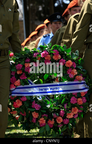 Israeliano soldati femmina portano ghirlande durante una cerimonia commemorativa per soldati caduti durante Yom Hazikaron giorno memoriale per i soldati caduti in Kiryat Shaul ebraica terreno di sepoltura nel nord di Tel Aviv Israele Foto Stock