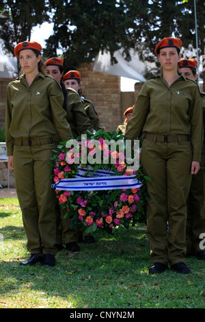 Israeliano soldati femmina portano ghirlande durante una cerimonia commemorativa per soldati caduti durante Yom Hazikaron giorno memoriale per i soldati caduti in Kiryat Shaul ebraica terreno di sepoltura nel nord di Tel Aviv Israele Foto Stock