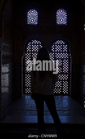 Silhouette di donna si fermò di fronte finestra ornata nell'Alhambra Palace, Granada, Spagna Foto Stock