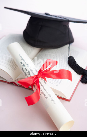 Il tappo di graduazione e diploma sul libro Foto Stock