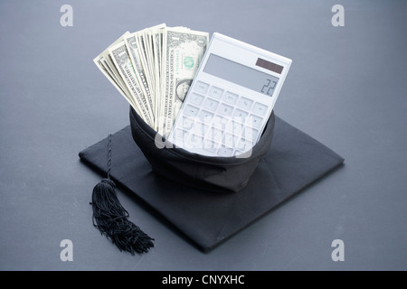 Il denaro e la calcolatrice nel tappo di graduazione Foto Stock
