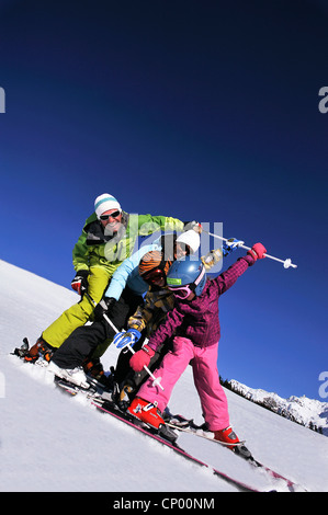 Famiglia con due figli su sci felicemente in piedi uno dopo l'altro in un snowbound pendio di montagna, Francia Foto Stock