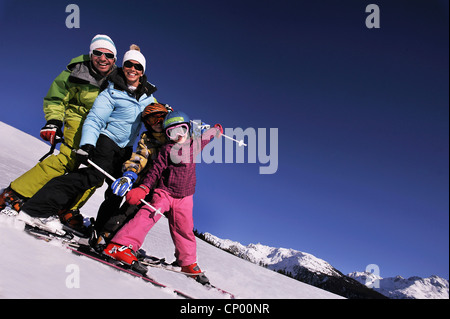 Famiglia con due figli su sci felicemente in piedi uno dopo l'altro in un snowbound pendio di montagna, Francia Foto Stock