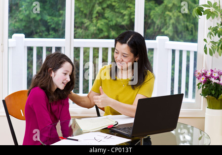 Asian preteen girl esprime sollievo dopo aver superato il test con le donne cinesi insegnante Foto Stock