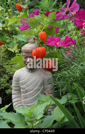 Giardino cosmo, messicano aster (Cosmos bipinnatus), Buddhistic scultura in un aiuola di fiori Foto Stock