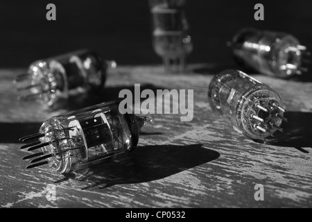 Molti dei vecchi tubi a vuoto giacente su di una superficie di legno. In bianco e nero Foto Stock