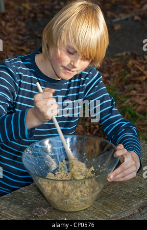 Ragazzo come preparare il pesto da self-raccolto di noci e semi di girasole, gli ingredienti vengono miscelati, Germania Foto Stock