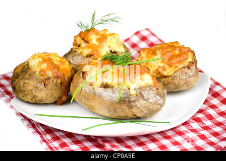 Patate ripiene coperto con il formaggio cheddar decorate con erba cipollina e aneto foglie in una piastra bianca Foto Stock
