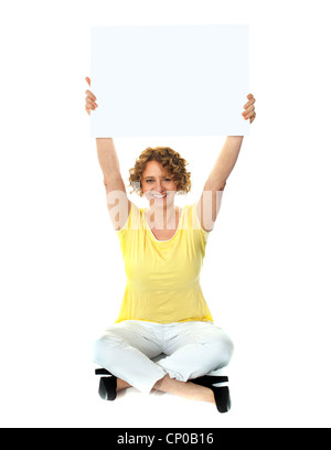 La donna seduta holding tabellone vuoto in una direzione verso l'alto Foto Stock