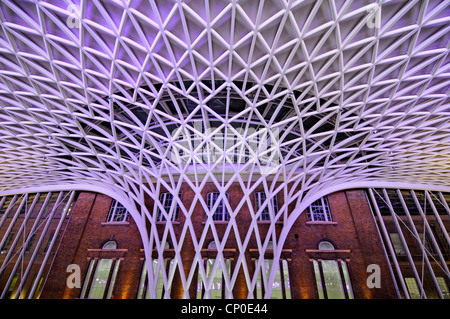 Acciaio strutturale a futuristico interno Londra Kings Cross stazione ferroviaria struttura tetto illuminato a notte vecchie mura oltre Inghilterra UK Foto Stock