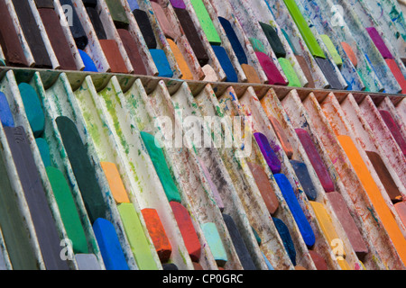 Close-up, angolo di visualizzazione della casella di grandi dimensioni di usato, confusa di colore pastello artista chalks giacente in righe verticali. Scatola riempita parzialmente. Foto Stock