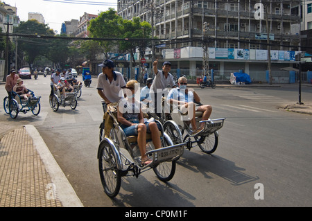 Vista orizzontale di risciò ciclo che trasportano i turisti occidentali di protezione da indossare maschere facciali per le strade della città di Ho Chi Minh, Vietnam. Foto Stock