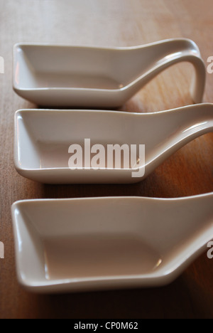 Tre vuoto bianco di ceramica di contenitori per alimenti in legno naturale sfondo tabella Foto Stock