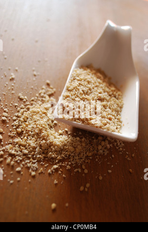 Gomasio fatta con semi di sesamo e sale in ceramica bianca sul contenitore di legno naturale sullo sfondo della tabella Foto Stock