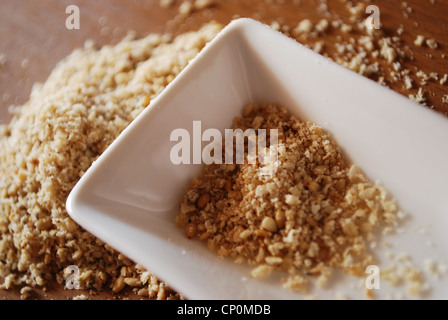 Gomasio fatta con semi di sesamo e sale in ceramica bianca sul contenitore di legno naturale sullo sfondo della tabella Foto Stock