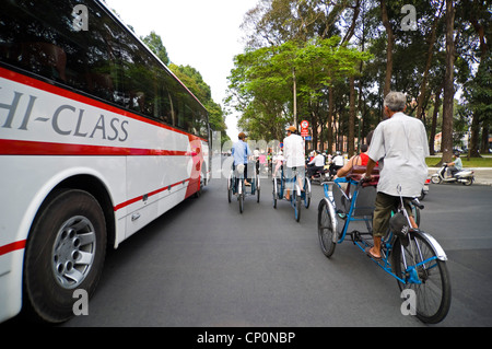 Vista orizzontale di risciò ciclo portante occidentale i turisti lungo il crazy strade di Ho Chi Minh City. Foto Stock