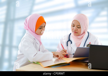 Due donne musulmane medico discute il referto del paziente Foto Stock