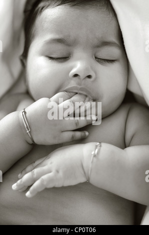 6 mesi di età Asian Indian Baby girl succhiare il suo i denti durante il sonno, in bianco e nero Foto Stock