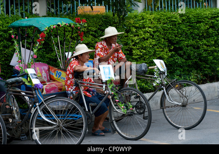 Il cyclo o biciclette risciò driver prendere un freno durante il Thai nuovo anno celebrazione sulla Strada di Sukhumvit Road, Bangkok, Thailandia. Foto Stock