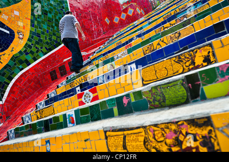 Un uomo si arrampica la Selaron's Scale (Escadaria Selarón), un mosaico scalinata fatta di piastrelle colorate, a Rio de Janeiro in Brasile. Foto Stock