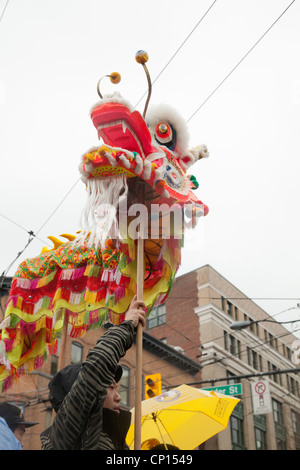 Un uomo mantiene la testa di un drago sopra la folla durante il 2012 Anno Nuovo Cinese parade di Vancouver. Foto Stock