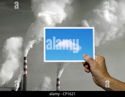 Mano Azienda Fotografia di cielo blu su fumaioli Foto Stock