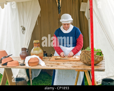 St Georges giorno Rievocazione Medievale al Castello di Richmond North Yorkshire una donna in abiti medievali a preparare verdura Foto Stock