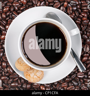Foto aerea di una tazza di caffè con amaretti sul lato con un background di freschi fagioli arrosto Foto Stock