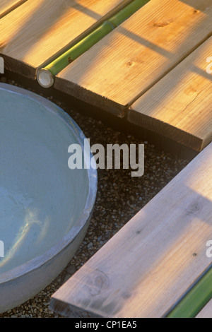 Close up di stile Giapponese funzione acqua con tubo di bambù impostato in decking Foto Stock