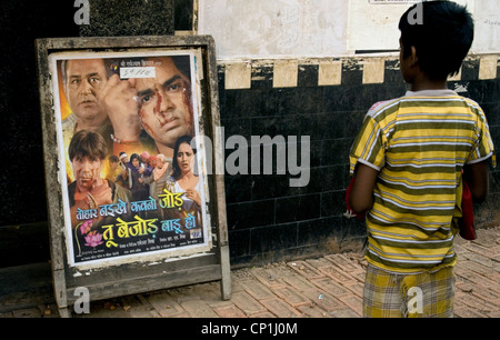 Ragazzo a guardare il poster di fronte del cinema in Kolkata Foto Stock