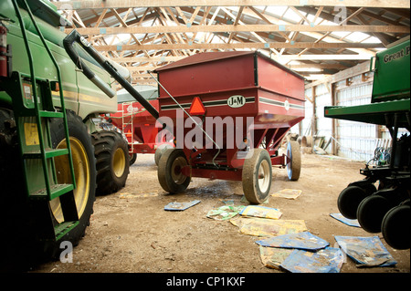 Fienile con le attrezzature agricole e trattori all'interno Foto Stock