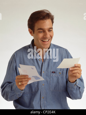 Giovane uomo cercando felice quando riceve una fattura, Berkshire, Inghilterra, Regno Unito Foto Stock