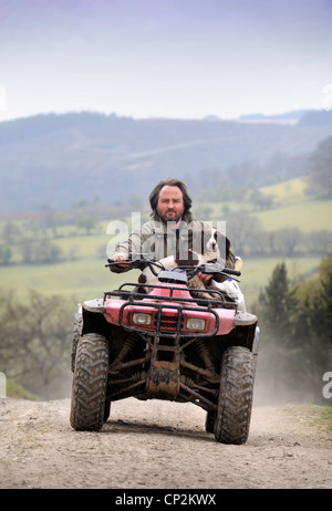 Un agricoltore su di una moto quad con il suo cane Spaniel Wales, Regno Unito Foto Stock