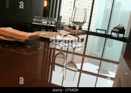 Bicchieri di vetro e si riflette sul altamente lucido tavolo da pranzo in hotel Conrad Tokyo, in Giappone. Foto Stock