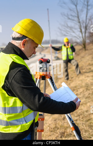 Geometri su autostrada geodesist lettura piani utilizzano tacheometer Foto Stock